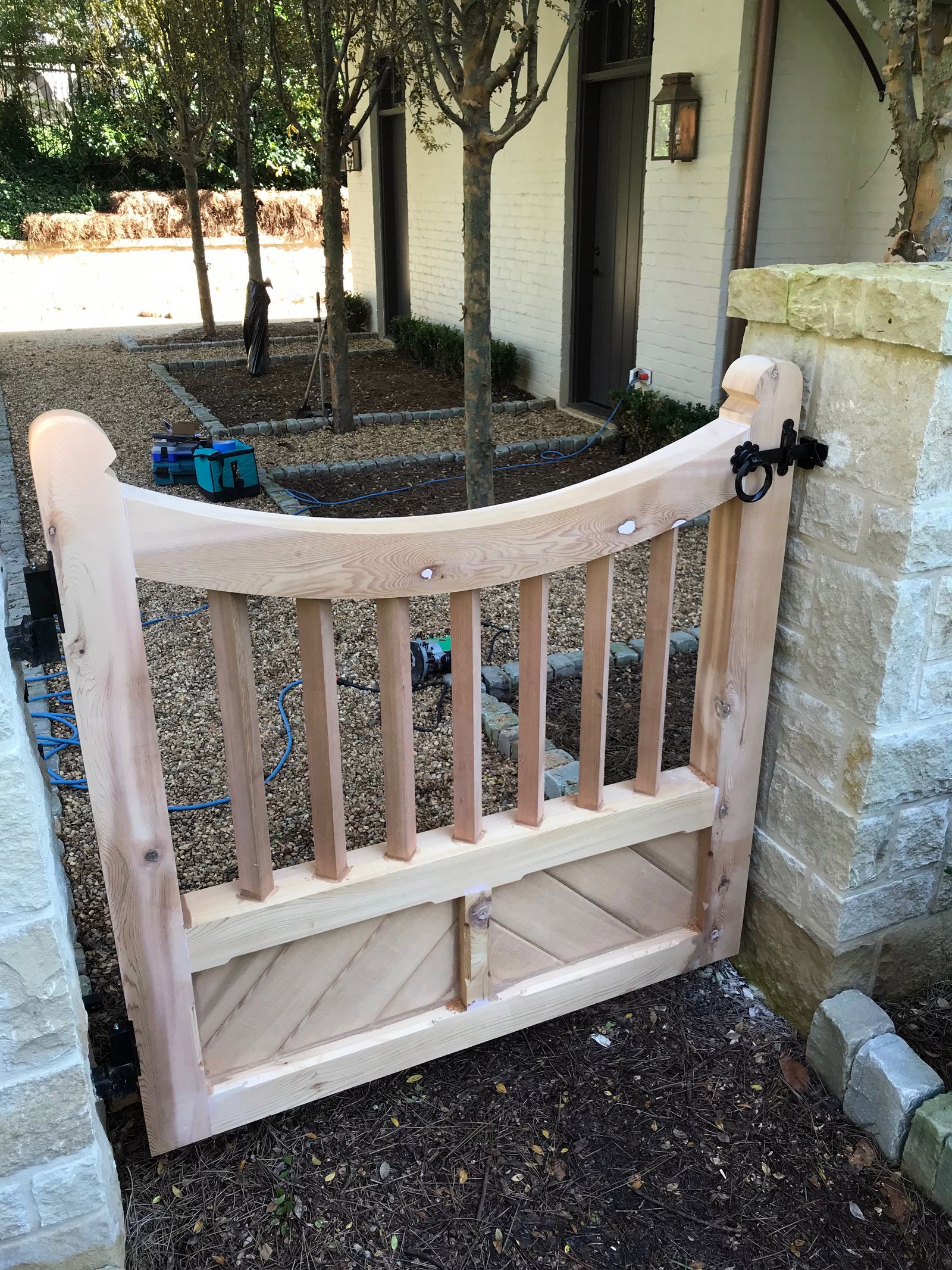 Curved-top wooden garden gate hung between stone columns