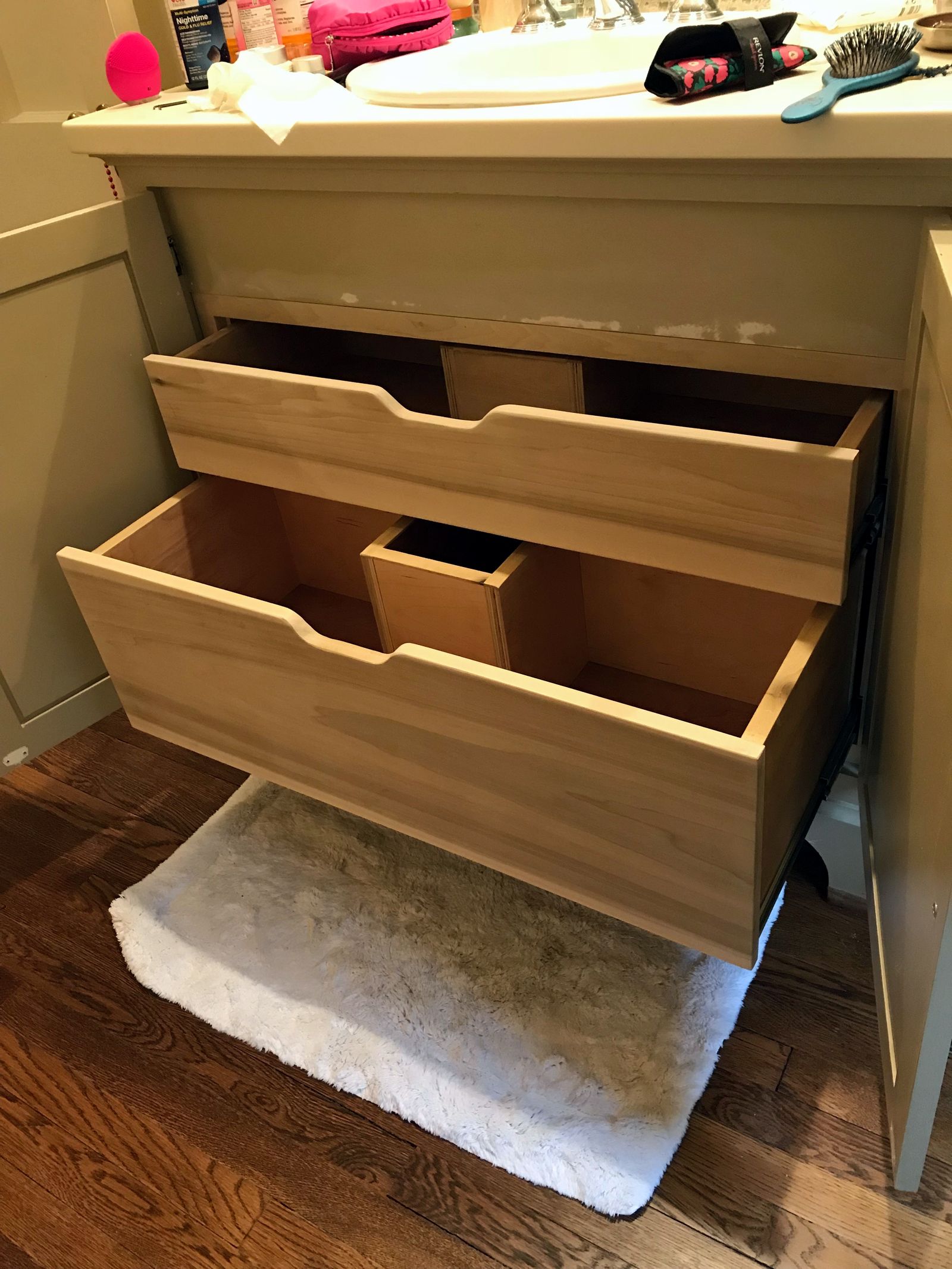 Open vanity drawers shaped around the plumbing space